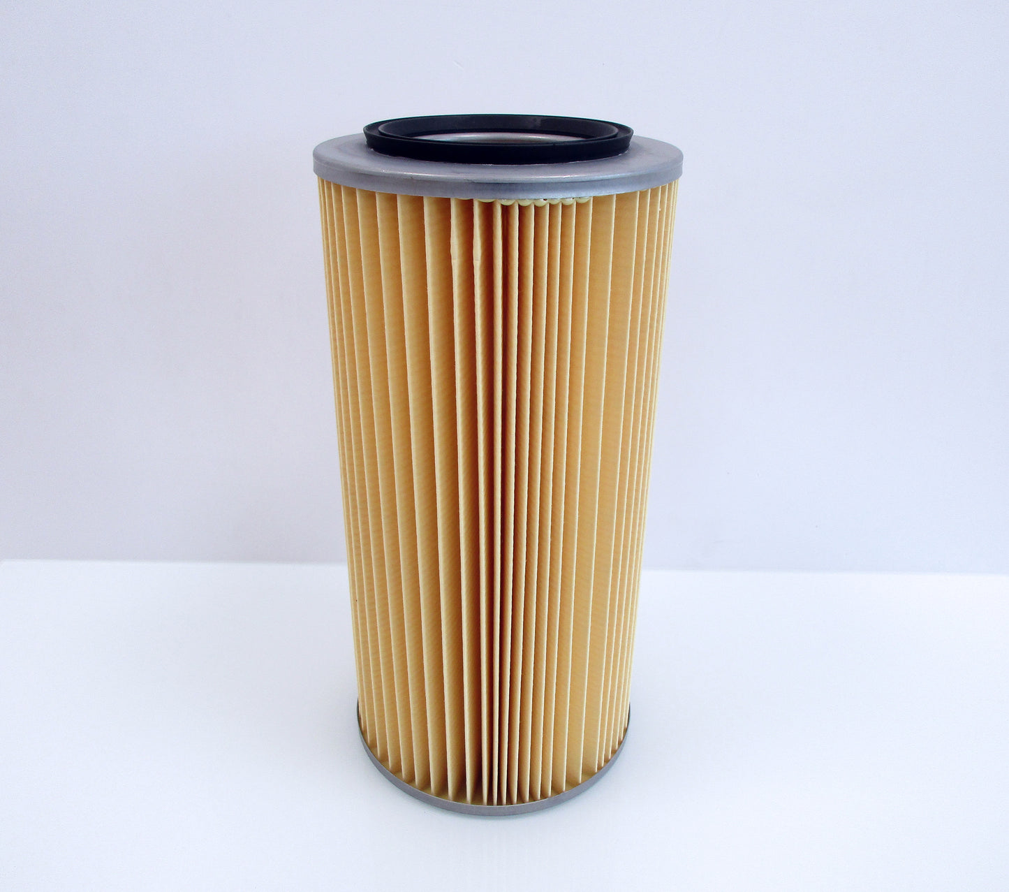A pleated cylindrical air filter with a tan paper body, a grey metal top, and a black rubber gasket, shown on a plain white background.