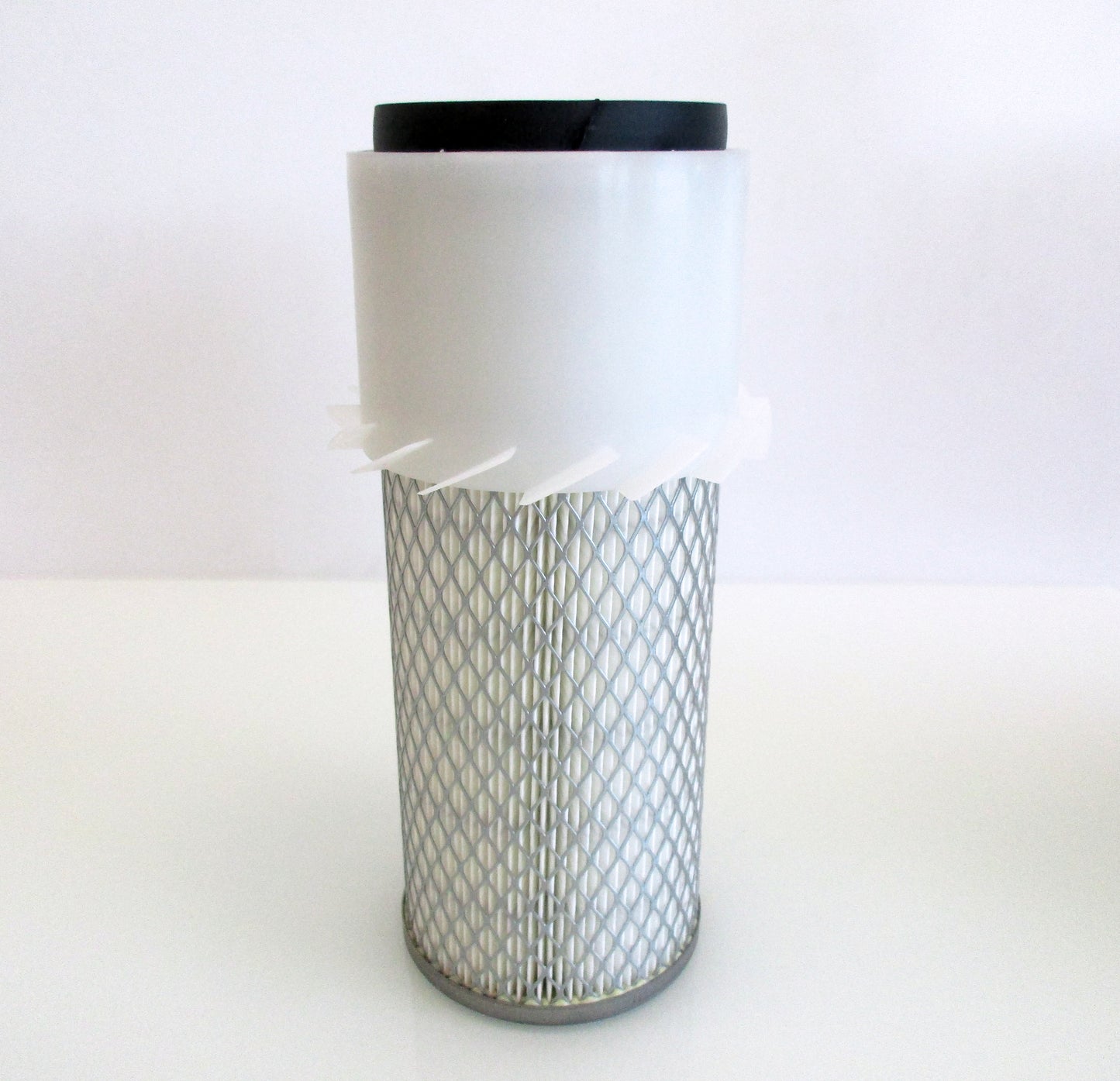A cylindrical replacement air filter with a white plastic upper section with fins, a black seal top and a white pleated media surrounded by metal mesh, with grey base shown on a white background.