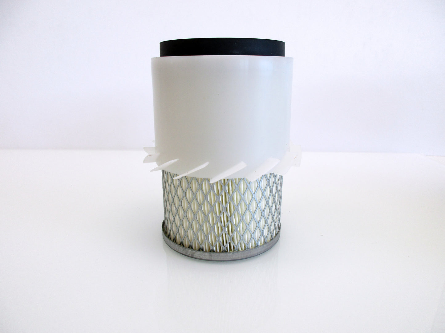 A cylindrical replacement air filter with a white plastic upper section with fins, a black top cap and a white pleated media surrounded by metal mesh, with grey base shown on a clean white background.