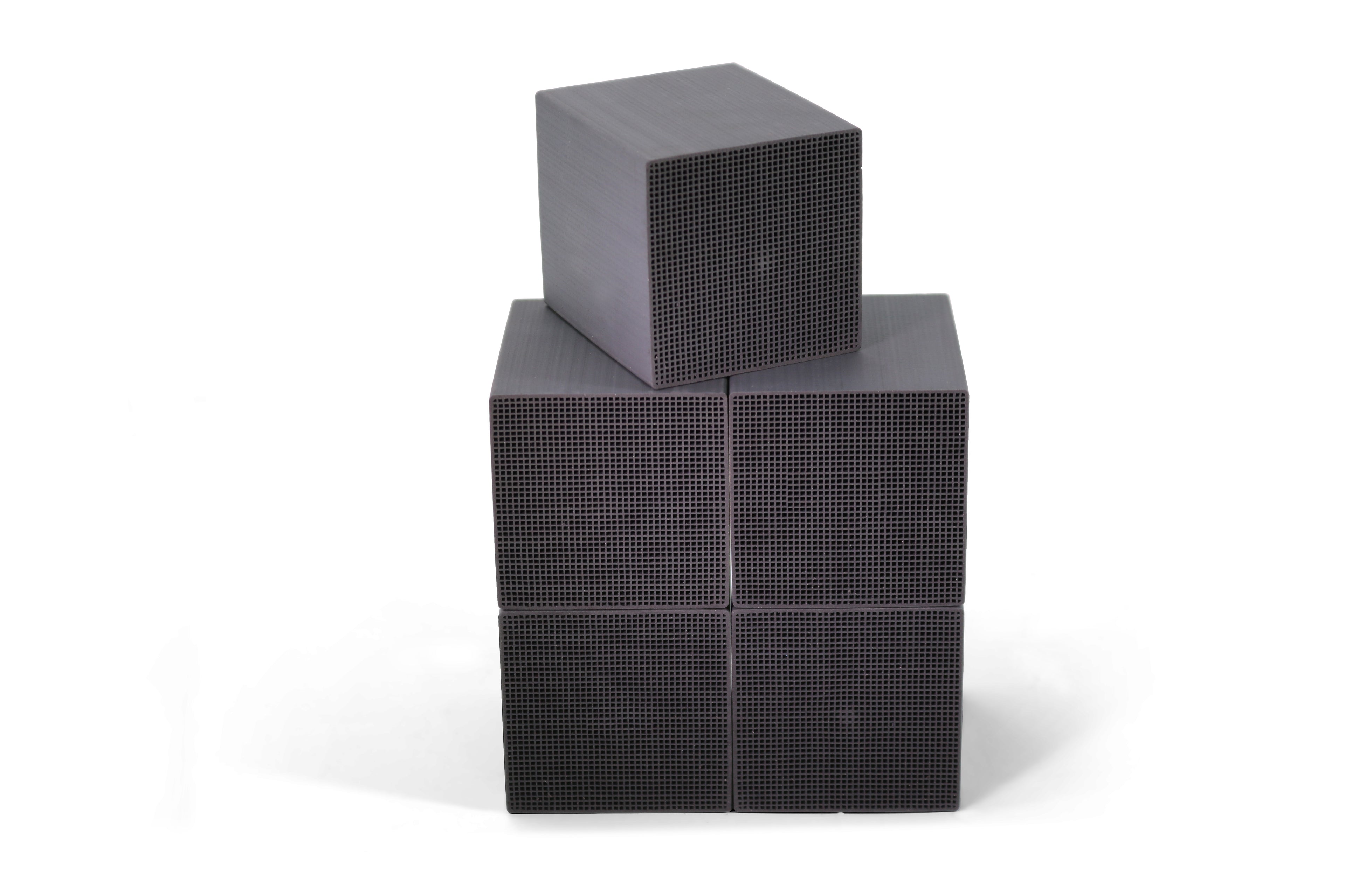 Three stacked black cube-shaped honeycomb activated carbon, set against a plain white background.