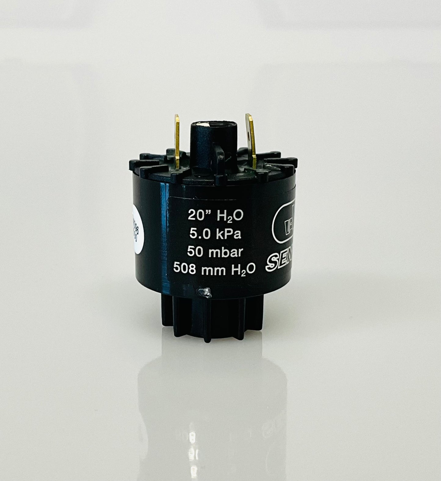 A black cylindrical electrical indicator with metal pins, featuring white printed specifications including '20" H2O', '5.0 kPa', '50 mbar', and '508 mm H2O'.