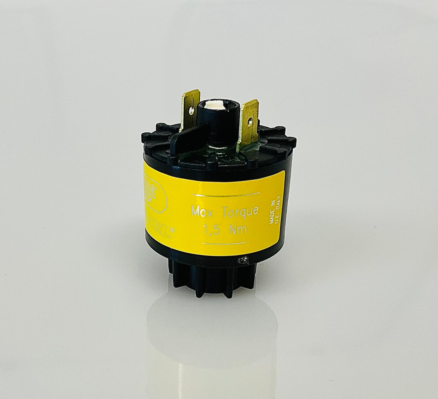 A small black cylindrical electrical indicator with two metal pins at the top, and a yellow label reading 'Max Torque', 1,5 Nm' and 'MADE IN U.E ITALY', shown on a reflective white surface.