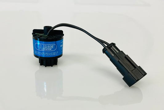 A black electrical indicator with a cable connection and yellow label, that reads 'Virgis Filter' and 'Sentinel'. Shown on a reflective white surface.