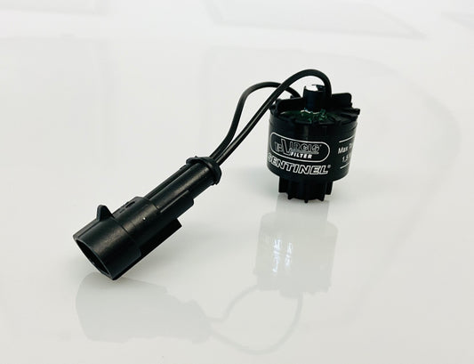 A black electrical indicator with a cable connection and a label, that reads 'Virgis Filter' and 'Sentinel'. Shown on a reflective white surface.