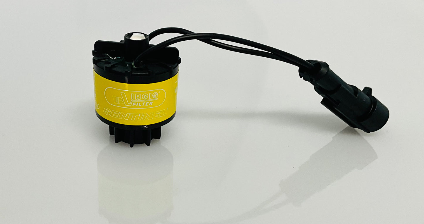 A black electrical indicator with a cable connection and yellow label, that reads 'Virgis Filter' and 'Sentinel'. Shown on a reflective white surface.