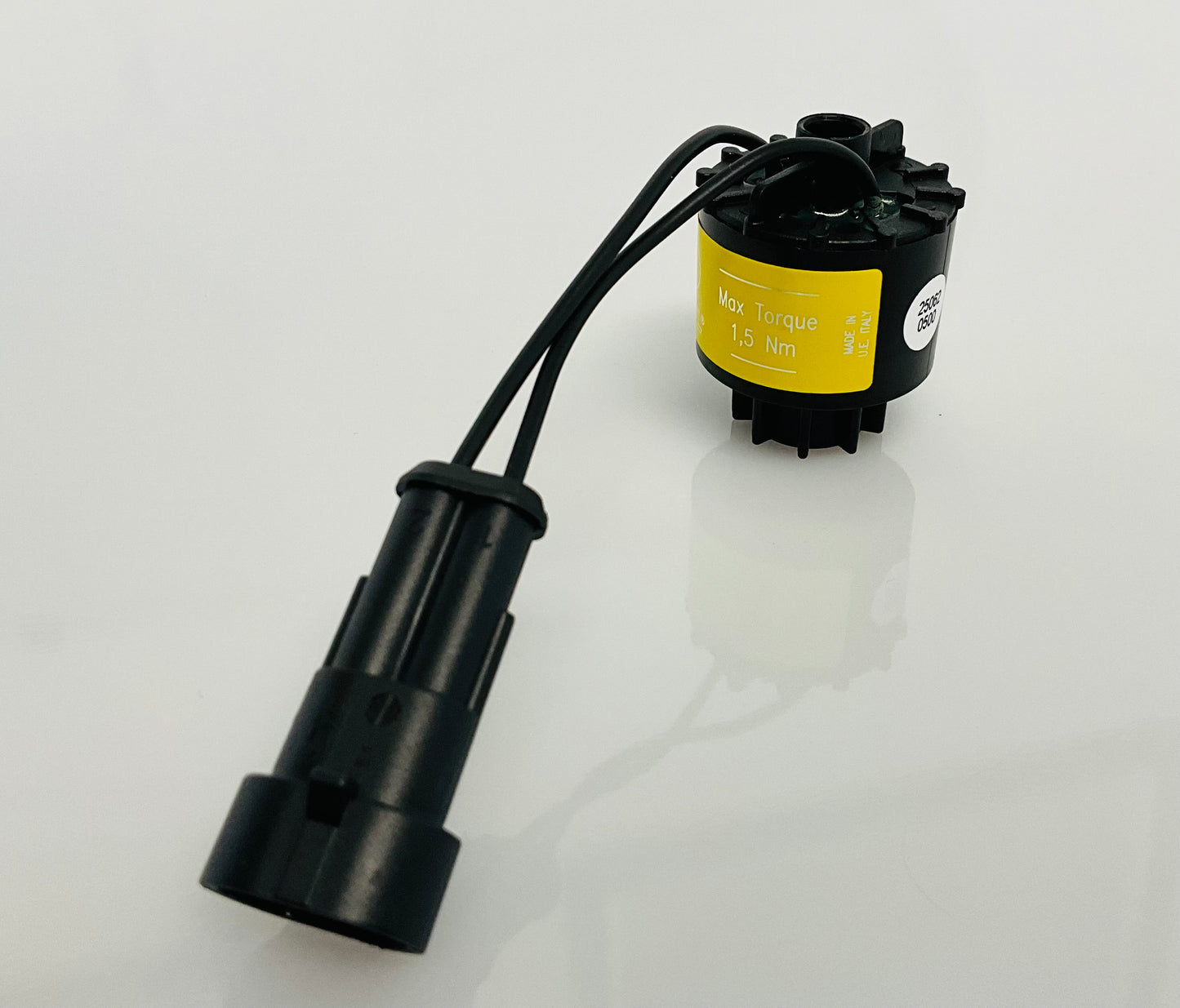 A black electrical indicator with a cable connection and yellow label, that reads 'Max Torque 1,5 Nm' and 'MADE IN U.E ITALY'. Shown on a reflective white surface.