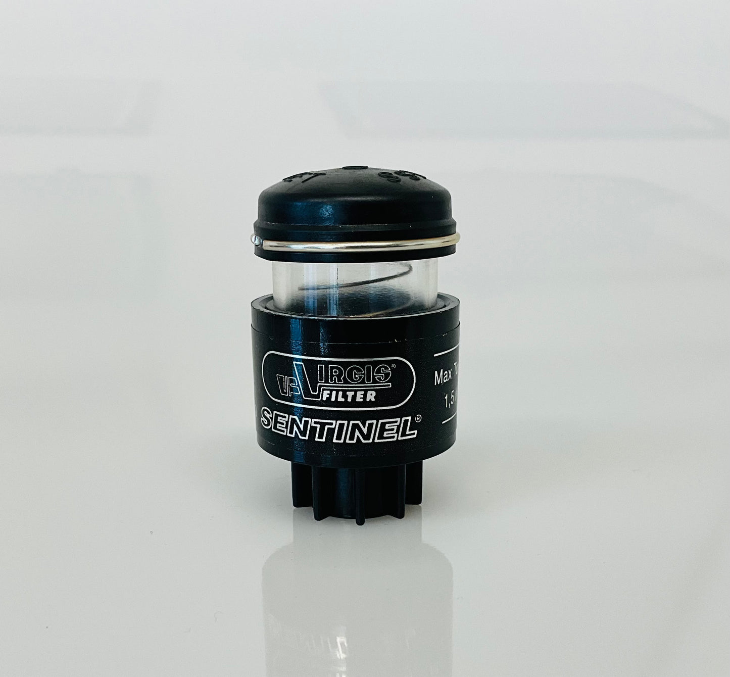A small black cylindrical optical indicator with press button top, labelled 'Virgis Filter' and 'Sentinel', shown on a reflective white surface.