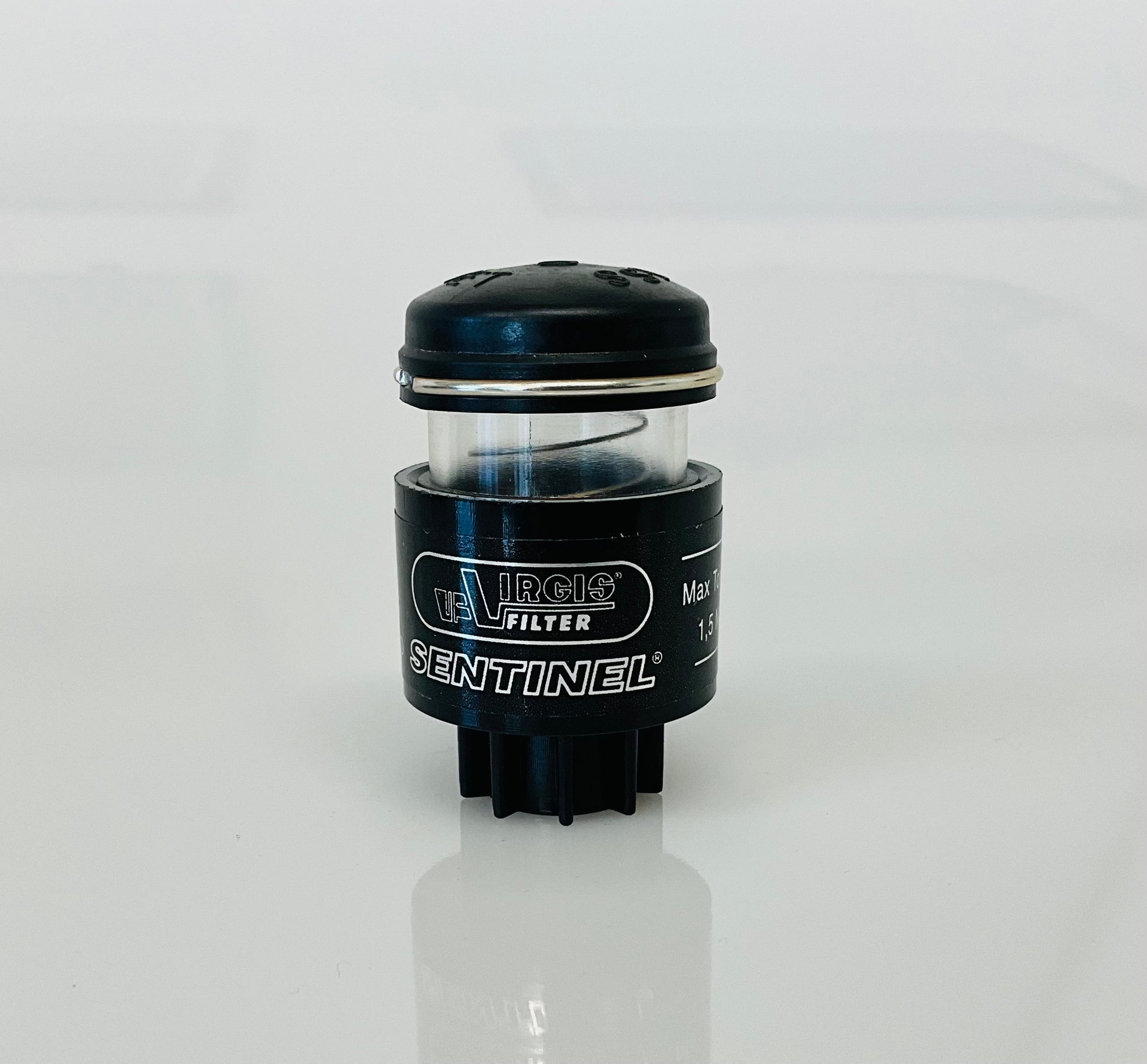 A small black cylindrical optical indicator with press button top, labelled 'Virgis Filter' and 'Sentinel', shown on a reflective white surface.
