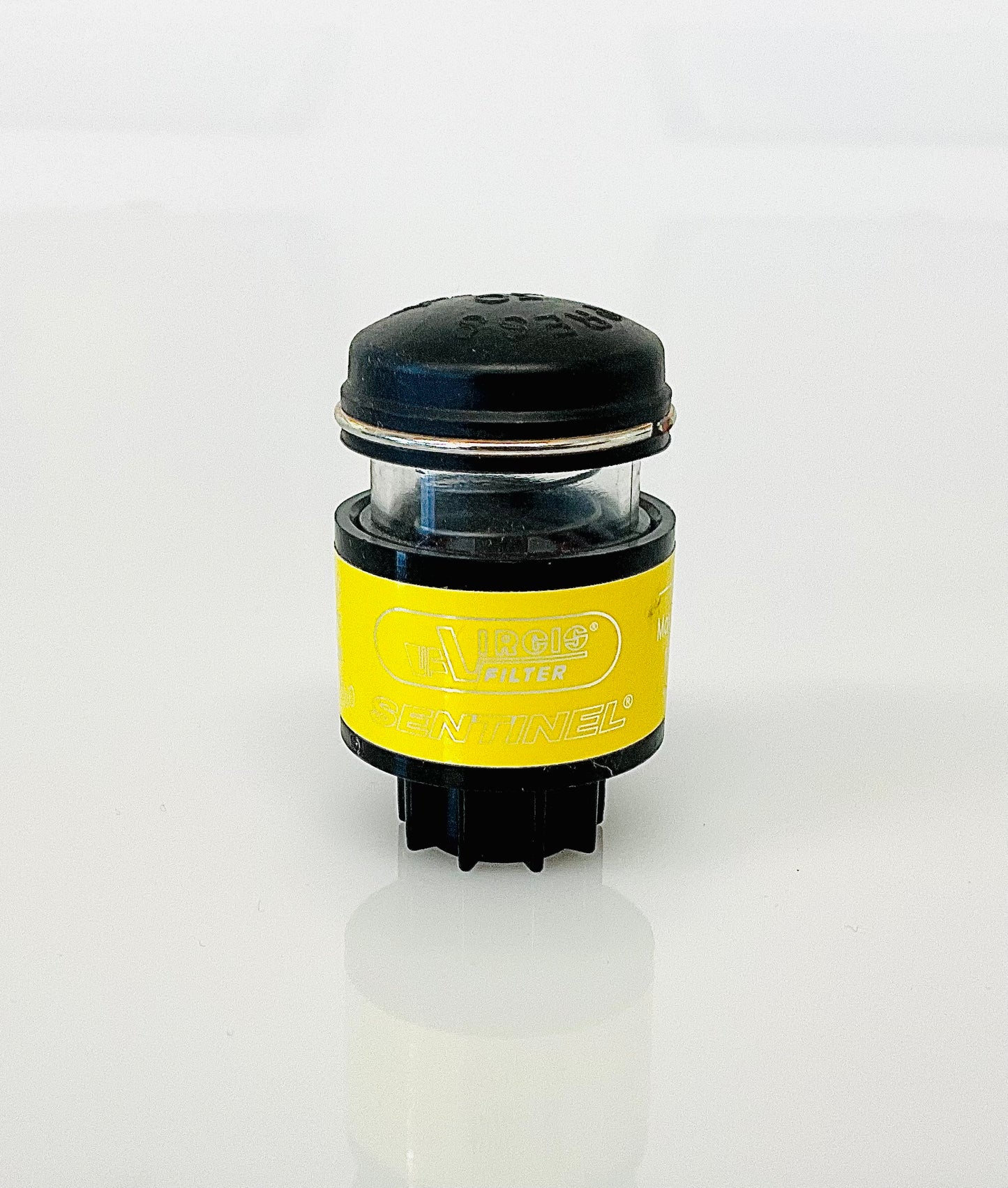 A small black cylindrical optical indicator with press button top, with a yellow label labelled 'Virgis Filter' and 'Sentinel', shown on a reflective white surface.